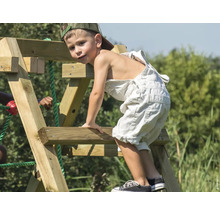 Junge klettert auf ein Holzspielgerät im Garten.