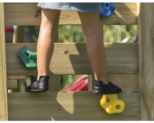 Kind klettert auf Kletterwand mit Klettersteinen