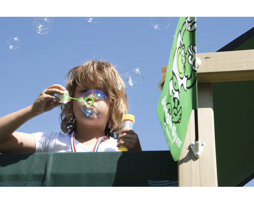Kind pustet Seifenblasen auf einem Spielplatz mit Jungle Gym Logo