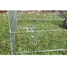 Nahaufnahme eines Drahtkäfigs mit Verriegelungsmechanismus für Kleintiere im Garten.