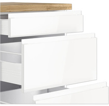 Detailansicht eines weißen Badezimmerschranks mit Schubladen und einer Holzplatte