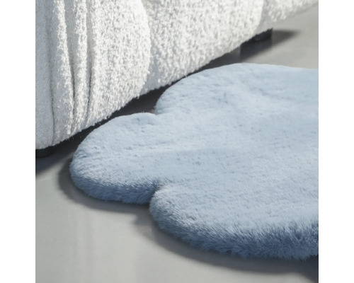 Blauer, wolkenförmiger Teppich neben einem Sofa.