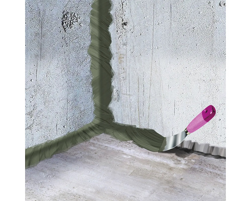 Ecke zwischen Wand und Boden wird mit einer Spachtelmasse abgedichtet, Spachtel mit Holzgriff