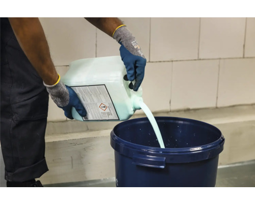 Eine Person gießt Flüssigkeit aus einem Kanister in einen Eimer.