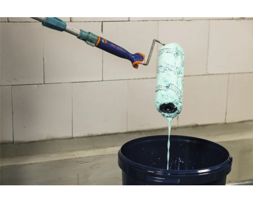 Farbe wird mit Farbroller in Farbeimer abgerollt.