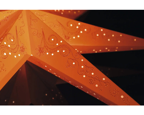 Nahaufnahme eines beleuchteten Papiersterns mit Lochmuster und dekorativen Ornamenten