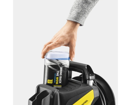 Ein Mann setzt einen Kanister mit Autoshampoo auf einen Hochdruckreiniger