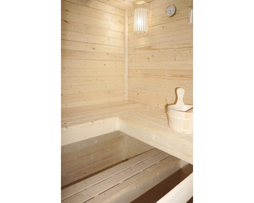 Innenraum einer Sauna mit Holzbänken, Lampe, Thermometer und Holzeimer
