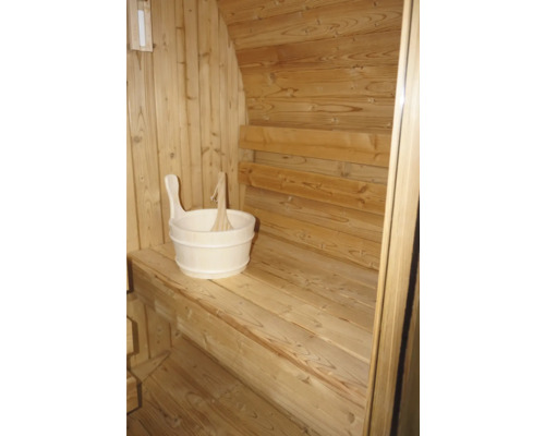 Innenansicht einer Sauna mit Holzwänden, Sitzbänken und einem Holzeimer mit Schöpfkelle