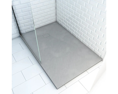 Ebene Duschwanne mit rechteckigem Abfluss und gläserner Duschabtrennung in einem Badezimmer mit weißen Fliesen.