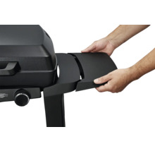 Ein Mann befestigt eine schwarze Seitenablage an einem schwarzen Gasgrill.