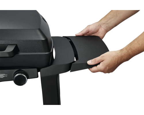 Ein Mann befestigt eine schwarze Seitenablage an einem schwarzen Gasgrill.