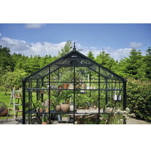 Gewächshaus mit Pflanzen und Gartenutensilien im Freien