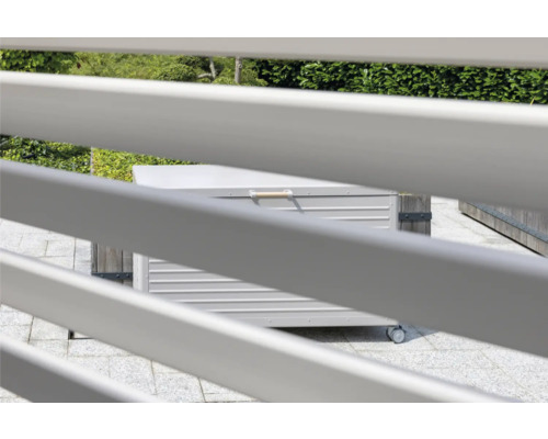 Gartenszene mit einer Aufbewahrungsbox aus Metall auf Rollen, gesehen durch einen Zaun