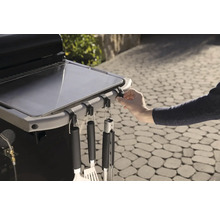 Detailaufnahme eines Grilltisches mit Grillbesteck an Haken.