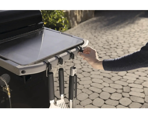 Detailaufnahme eines Grilltisches mit Grillbesteck an Haken.