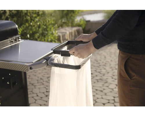 Person befestigt Müllbeutel an Grillwagen für eine saubere und praktische Grillumgebung.