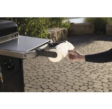 Grill mit Papierrollenhalter und Hand beim Abrollen von Papier