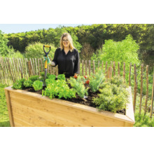 Hochbeet aus Holz mit Gemüsepflanzen und einer Frau mit Spaten