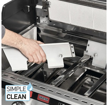 Innenansicht eines Grills mit einer Hand, die eine Edelstahlabdeckung einsetzt