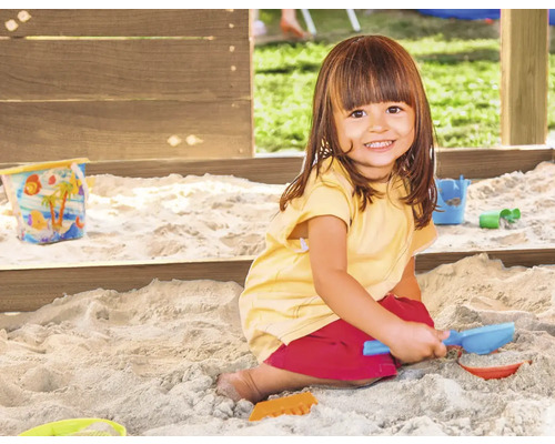 Ein Kind spielt im Sandkasten mit Sandspielzeug.