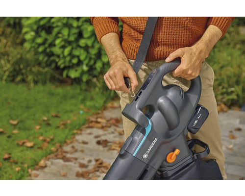 Eine Person befestigt den Tragegurt an einem Akku-Laubsauger von Gardena