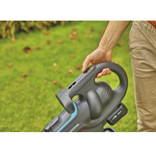 Person bedient einen Akku-Laubsauger im Garten.