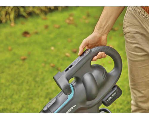 Person bedient einen Akku-Laubsauger im Garten.