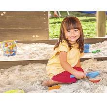 Mädchen spielt mit Sandkastenspielzeug im Sandkasten
