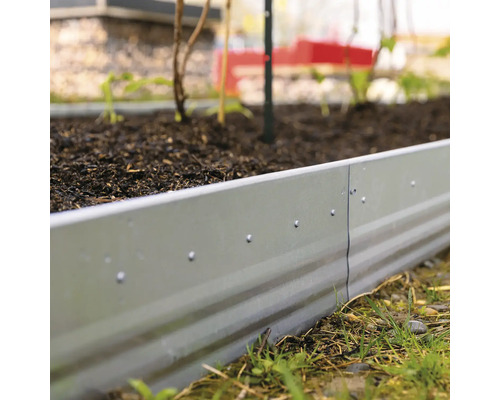 Hochbeet aus Metall im Garten mit Erde befüllt