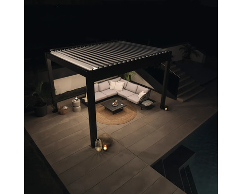 Terrasse mit Lamellendach, Ecksofa und Gartentisch bei Nacht