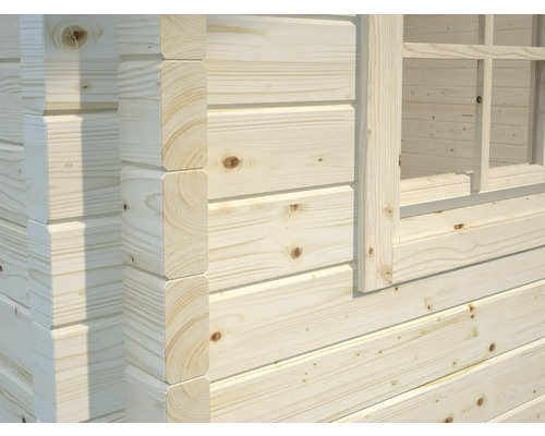 Detailansicht eines Holzhauses mit Fenster und Blockbohlenbauweise