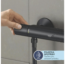 Eine Hand bedient eine schwarze Grohe Duscharmatur an einer gefliesten Wand.