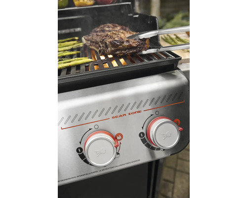 Grill mit Steak und Spargel wird mit Zange gewendet