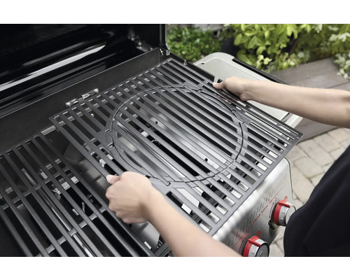 Person legt Grillrost in einen Gasgrill.