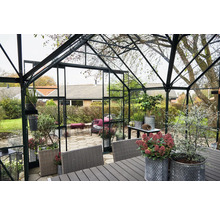 Gewächshaus mit Möbeln und Pflanzen im Garten.