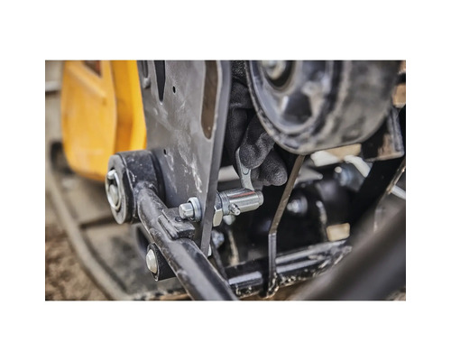 Detailansicht einer Rüttelplatte mit Sicherungsstift in Betätigung durch eine Person mit Handschuhen.