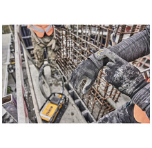 Eine Person trägt DeWalt-Arbeitshandschuhe auf einer Baustelle