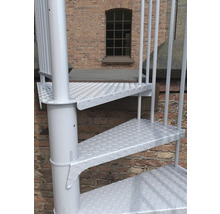 Detailaufnahme einer weißen Wendeltreppe vor einer Backsteinmauer.