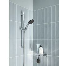 Duschstange mit Handbrause und Ablage in einer hell gefliesten Dusche.