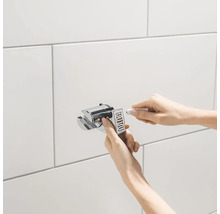 Installation einer Duschhalterung an einer gefliesten Wand mit Klebstoff.