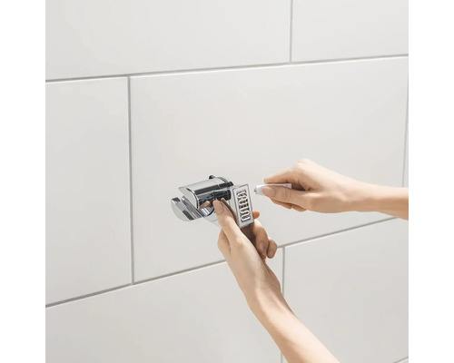 Installation einer Duschhalterung an einer gefliesten Wand mit Klebstoff.