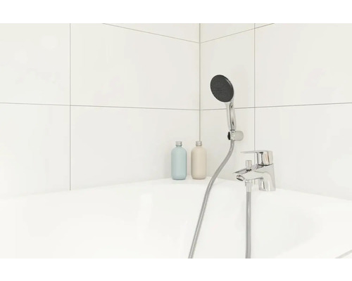 Badezimmer mit Armatur, Brausekopf und zwei Flaschen auf dem Badewannenrand