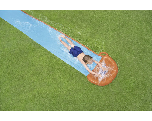 Draufsicht eines Kindes, das auf einer Wasserrutsche im Garten liegt