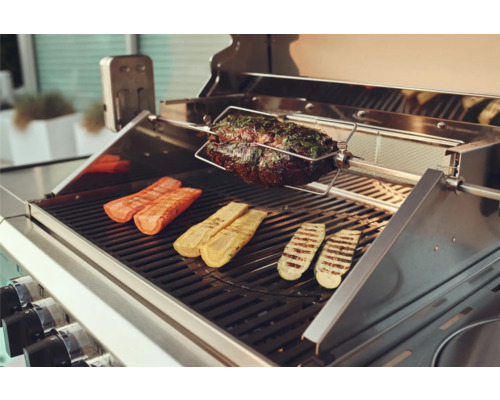 Grill mit Braten am Drehspiess sowie Zucchini und Karotten