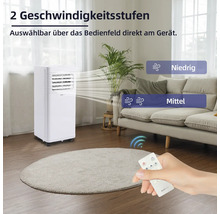 Mobiles Klimagerät mit zwei Geschwindigkeitsstufen und Fernbedienung in einem Wohnzimmer.