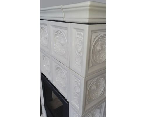 Detailansicht eines Kaminofens mit weißen, floral verzierten Kacheln