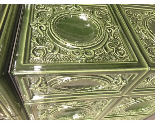 Detailaufnahme eines Ofens mit Keramikfliesen und floralem Muster