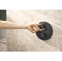 Hand bedient schwarzen Duschthermostat von Grohe an gefliester Wand