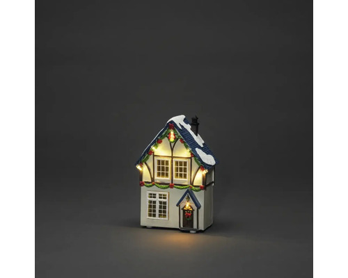 Beleuchtetes dekoratives Weihnachtshaus mit Schnee auf dem Dach